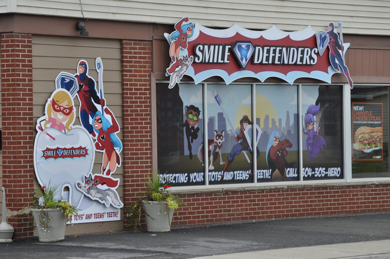 Photo of a Smile Defender office's outside sign and window artwork - featuring a Smile Defender Scene.