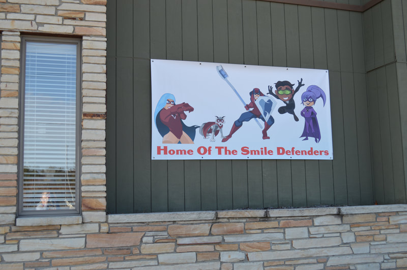 Photo of a smile defender banner on the side wall of a dental office.