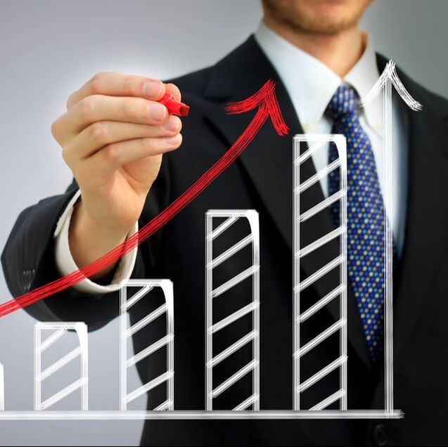 Picture of a business man in a suit and tie, using a red marker to make notes on a growth chart.