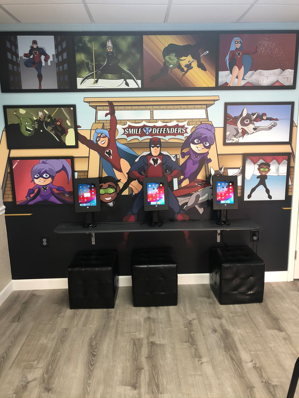 Photo of the inside of a Smile Defender office, showing the iPad station and wall mural featuring al Smile Defender Characters.